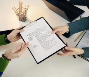 High angle view of employee giving his cv to manager while they sitting at interview
