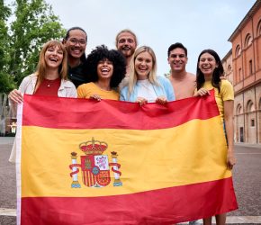 Multiracial group of friends holding the Spanish flag with pride, celebrating patriotism and their passion for sports, football. Energetic and cheerful outdoors, reflecting unity and enthusiasm