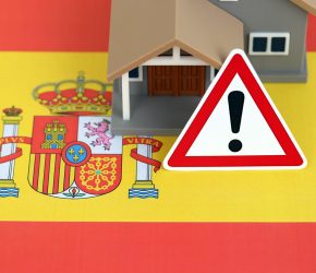 Residential house with alert sign on Spanish flag close up. Concept of Squatting in Spain. Okupas problem